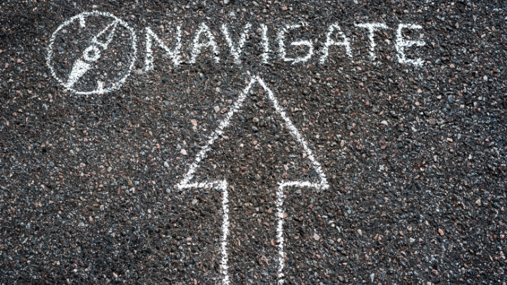 Word 'NAVIGATE' with an arrow written in chalk on the pavement