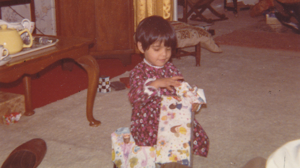 Pam as a little girl opening a Christmas present